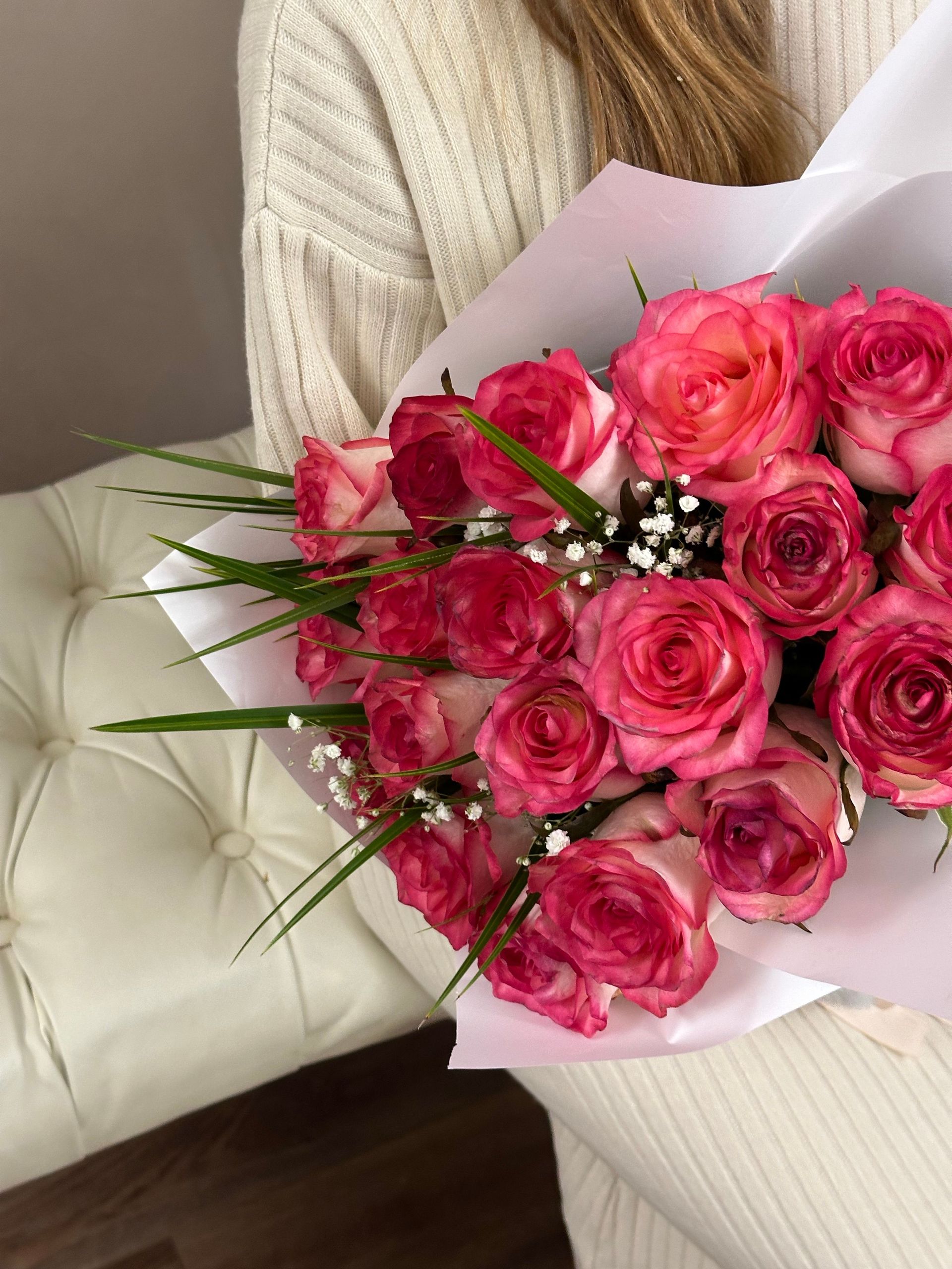 A stunning bouquet of pink roses elegantly arranged, placed on a cream leather chair, perfect for romantic occasions.